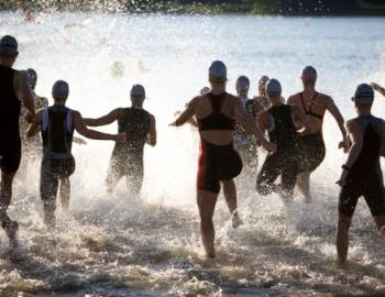 group of athletes running into water for swim race 
