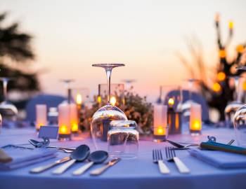 table set with candles, wine glasses and silverware at an outdoor table at sunset