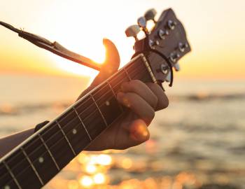 person playing guitar with body of water in the background