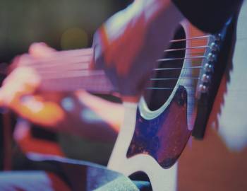 close up on hands of person playing guitar