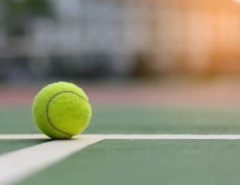 focus on a close up of a tennis ball on a green tennis court