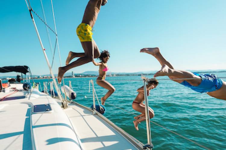happy friends diving from sailboat