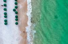 Aerial view of green umbrellas and the beach and surf of Destin, FL
