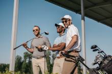 three men holding golf clubs