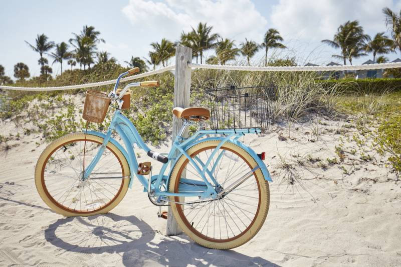 bike on beach propped on fence