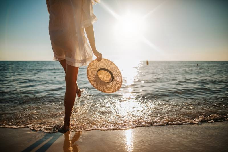 woman on beach with hat in hand