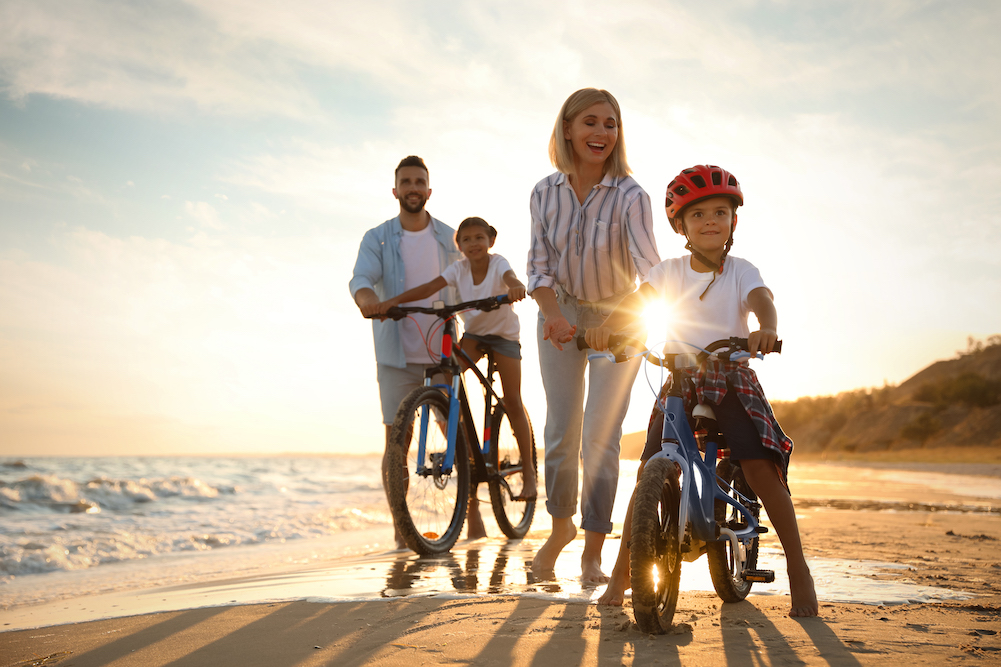 happy family riding bikes on beach