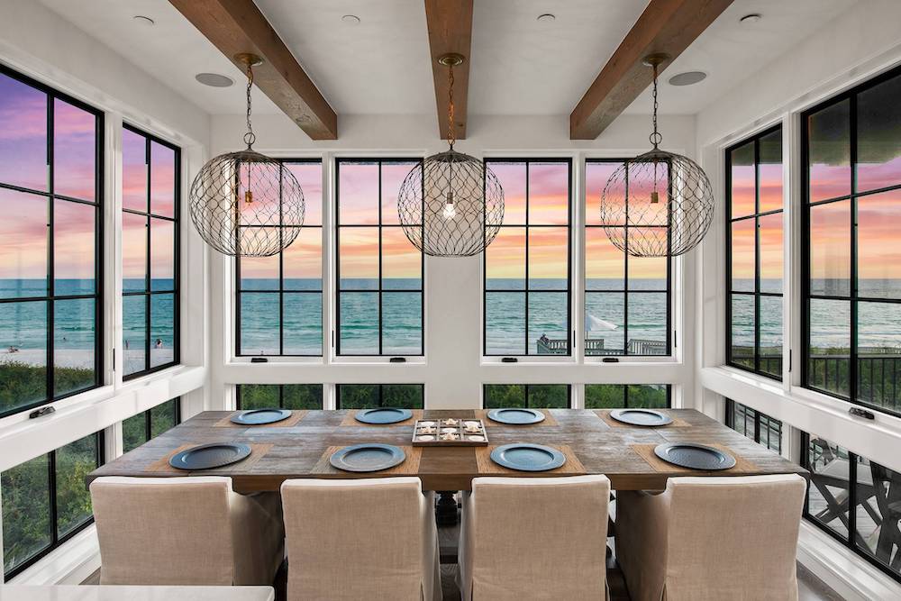 dining table with view of gulf coast and sunset out the large windows 