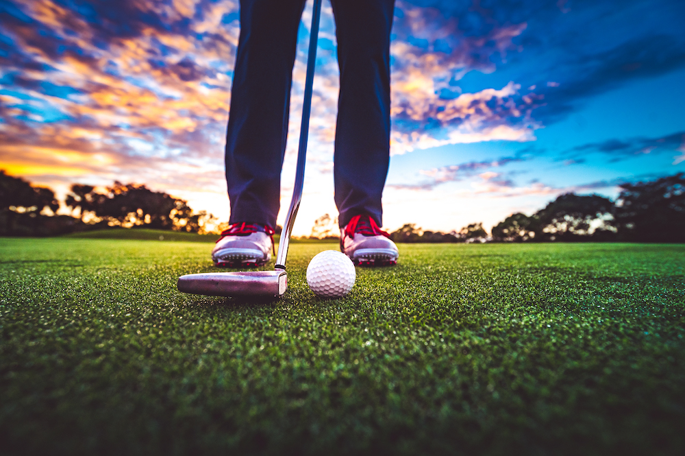 close up on a golfer's feet as he tee's up his ball and club.