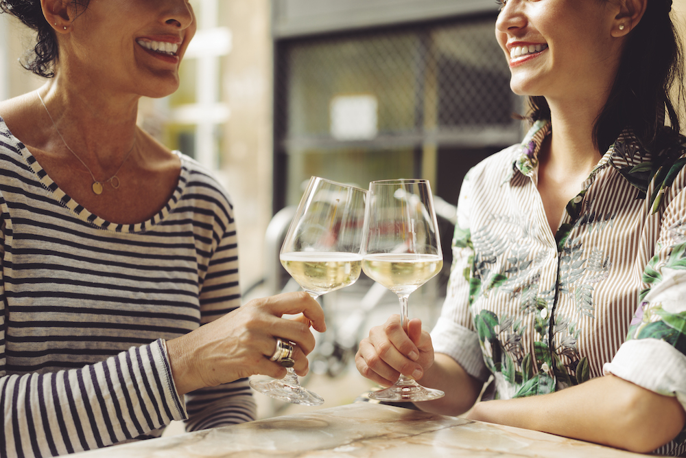 mother and daughter drinking white wine at a daytime meal
