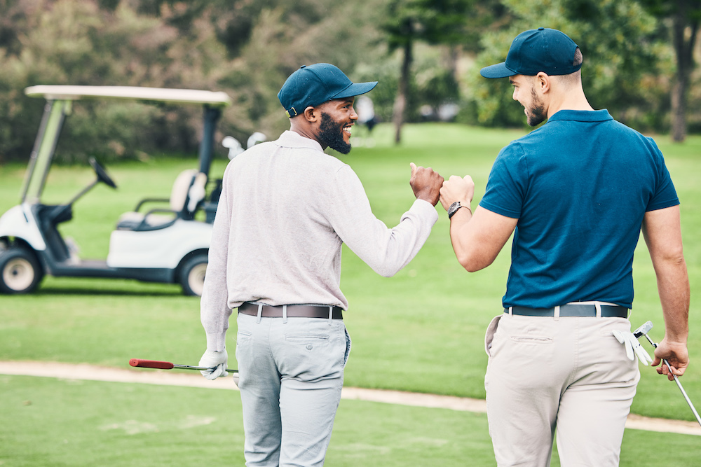 two male friends walking toward a golf cart 